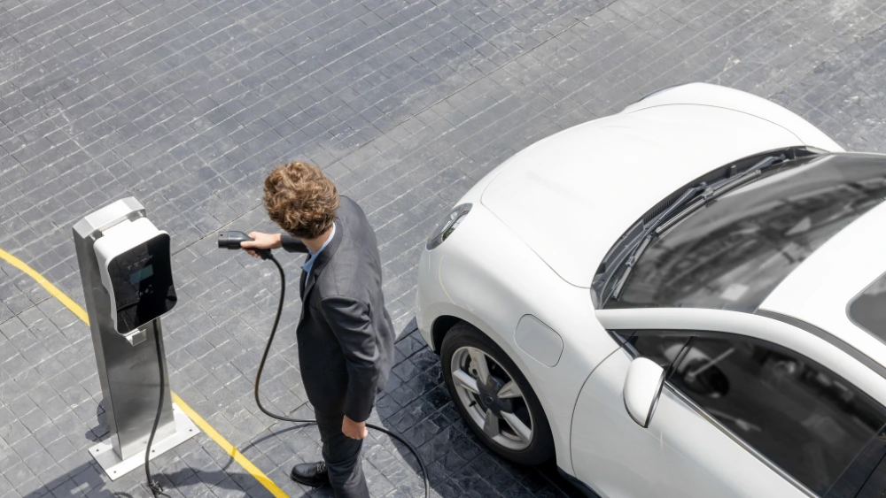 Installateur certifié IRVE branchant une borne de recharge pour véhicule électrique sur un parking d'entreprise dans le Morbihan
